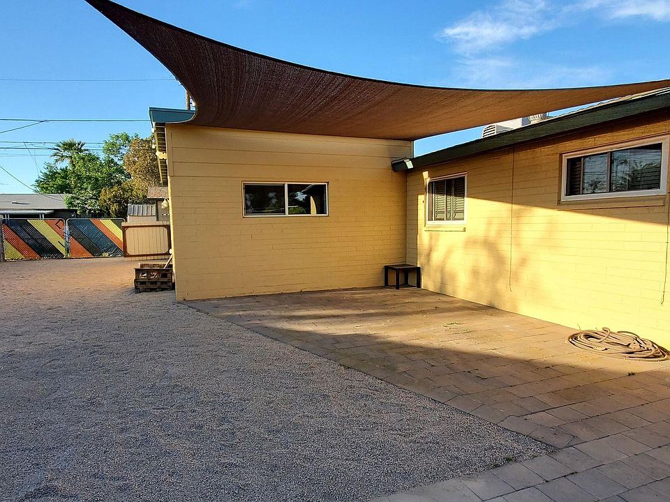 Large private, fenced yard with covered patio/parking area, umbrella, firepit and patio furniture