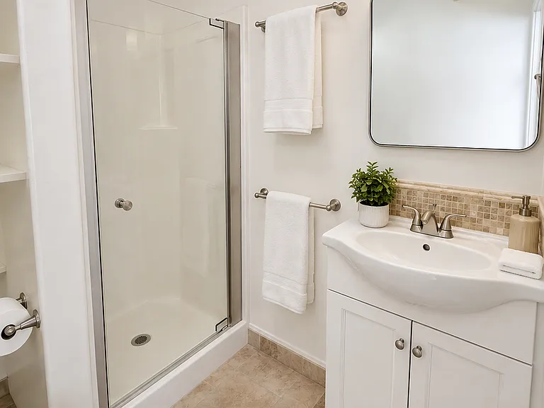 A bright, modern 3/4 bath with a sleek glass step-in shower.