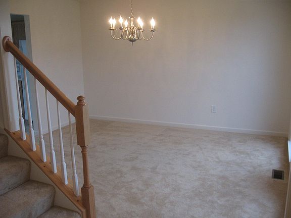View from front door into the front dining or living room area. To the left of the stairs a hallway leads to half bath, garage, hall closet and great room (family room/dining/kitchen).