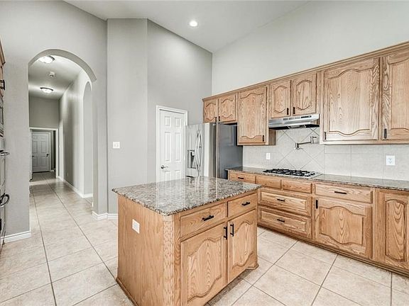 Kitchen includes granite counters, gas cook top with pot filler faucet, stainless steel appliances, recessed canned lighting, island and breakfast bar.