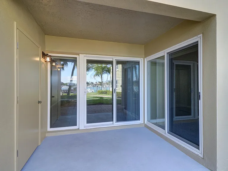 Glass doors from living room and bedroom open to private waterfront patio with storage room