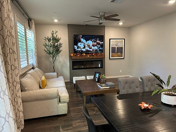 Living room with electric fireplace open to modern kitchen.