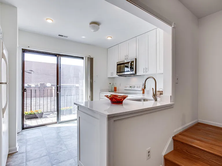 Sunny kitchen with sliders to private balcony.