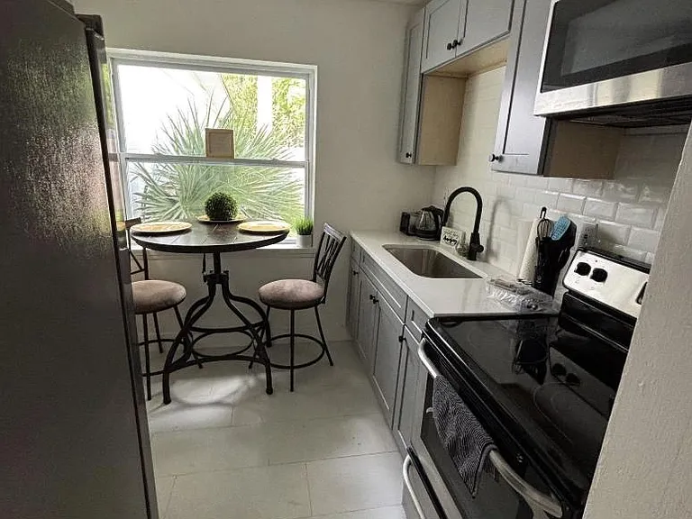 Efficient galley kitchen with ample cabinet storage, stainless appliances, and a sunny breakfast nook by the window.