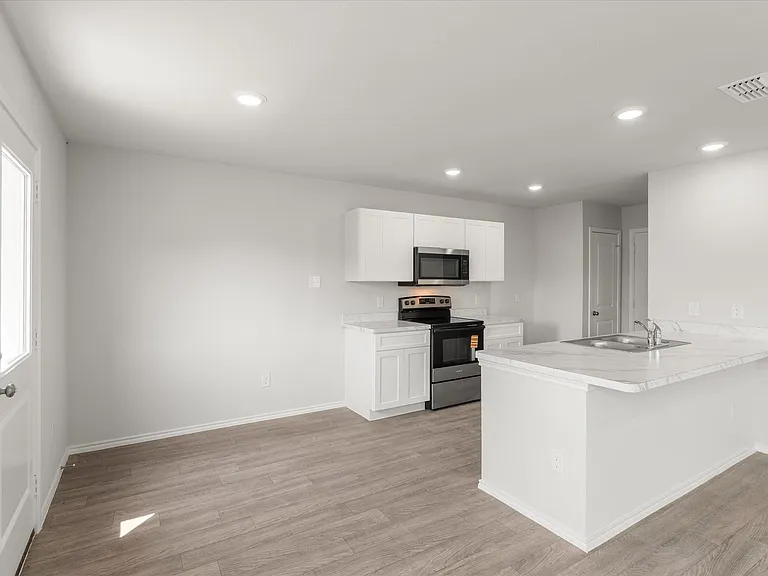 Open concept kitchen featuring stainless steel appliances, white cabinetry, and light-toned countertops