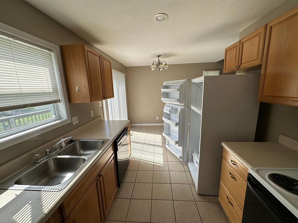 Bright galley-style kitchen with tile throughout the duplex. Recessed lighting and window blinds - clean and move-in ready.