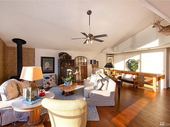 Standing in the living room looking towards the front door. Note the high vaulted ceilings, the beautiful new hickory floors, Lopi wood stove and the abundance of living space this home has to offer. Wall of windows showcasing the amazing views just to the left of the photo. 