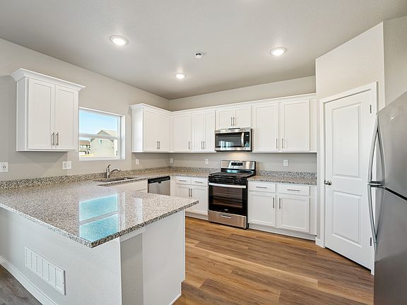 The kitchen has stainless steel appliances and plank flooring.