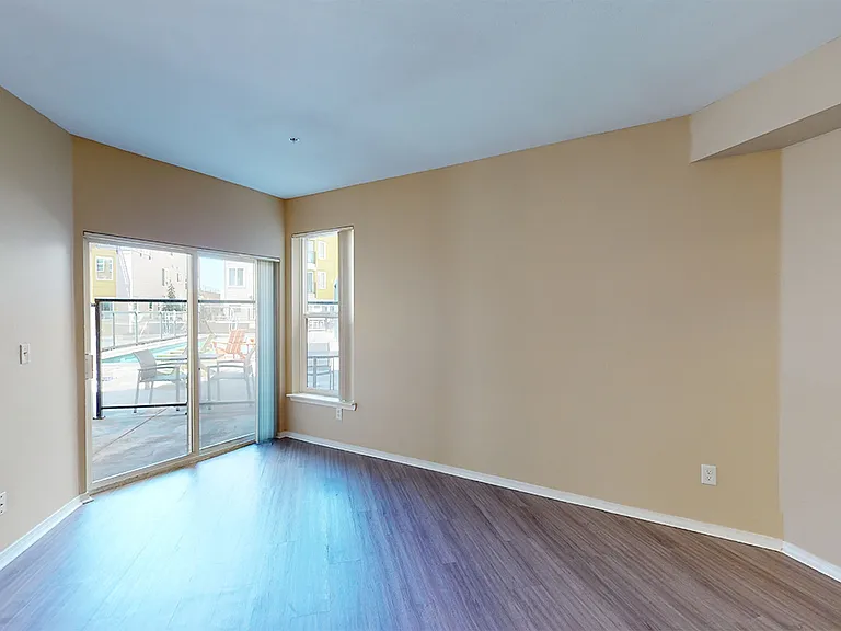 Apartment living room with wood-style flooring and balcony in select homes.