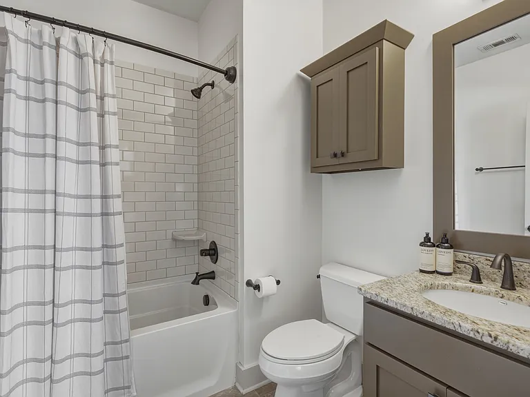 Shower/tub combo in bathroom 3, along with a hanging cabinet and vanity for storage.