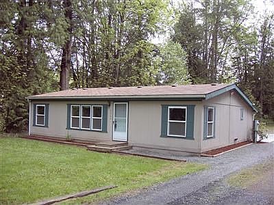 Front of the home with gravel drive along side.