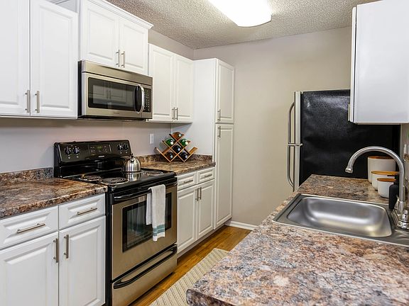 This modern galley-style kitchen features stainless steel appliances, white cabinetry, and expansive countertopsperfect for prepping, cooking, and entertaining.