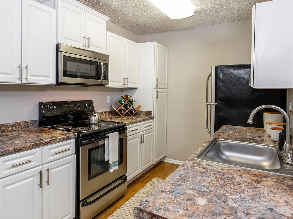 This modern galley-style kitchen features stainless steel appliances, white cabinetry, and expansive countertopsperfect for prepping, cooking, and entertaining.