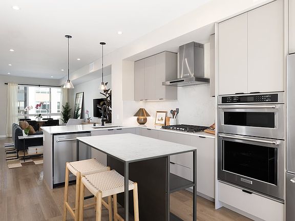 Signature Collection I 3-Bedroom Townhome Kitchen with light grey cabinetry, white marbled quartz countertops, and upgraded stainless steel appliances
