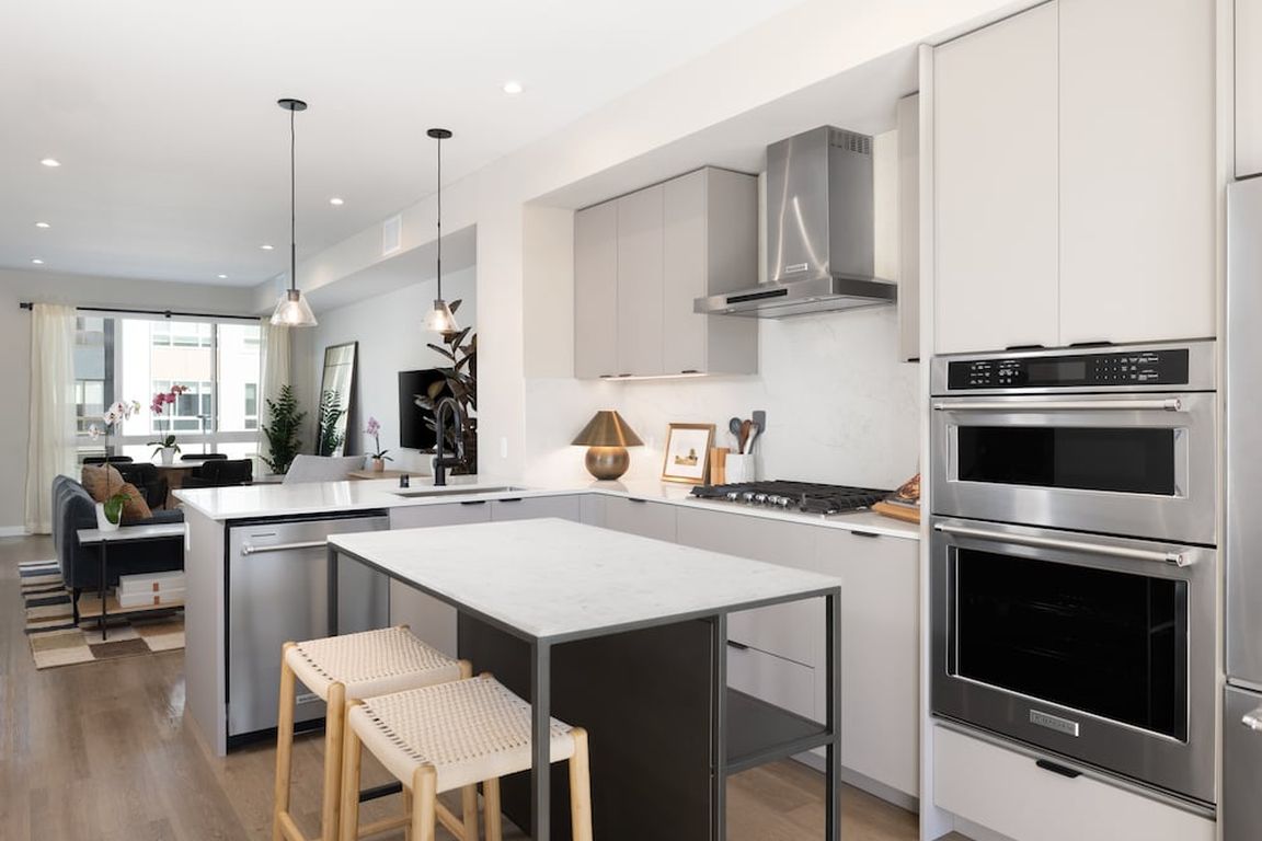 Signature Collection I 3-Bedroom Townhome Kitchen with light grey cabinetry, white marbled quartz countertops, and upgraded stainless steel appliances