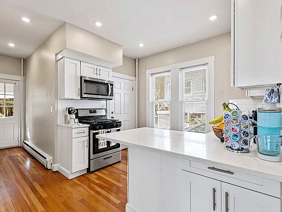 kitchen with quartz countertop, stainless steel appliances, hardwood floors, washing machine, dryer, and dishwasher