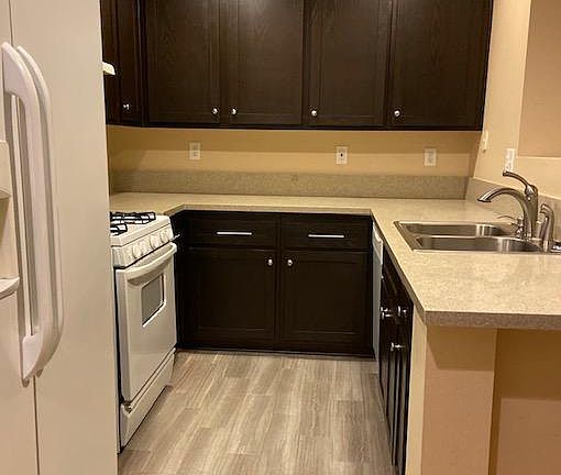 Espresso-colored_ cabinets, quartz countertops, and stainless steel sink with garbage disposal.