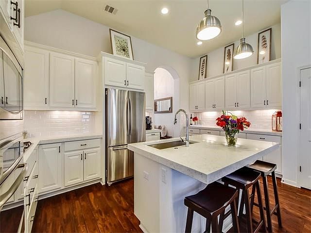 outstanding clean crips kitchen with Quartz counter tops, subway tile backsplash, painted cabinets and stainless appliances.