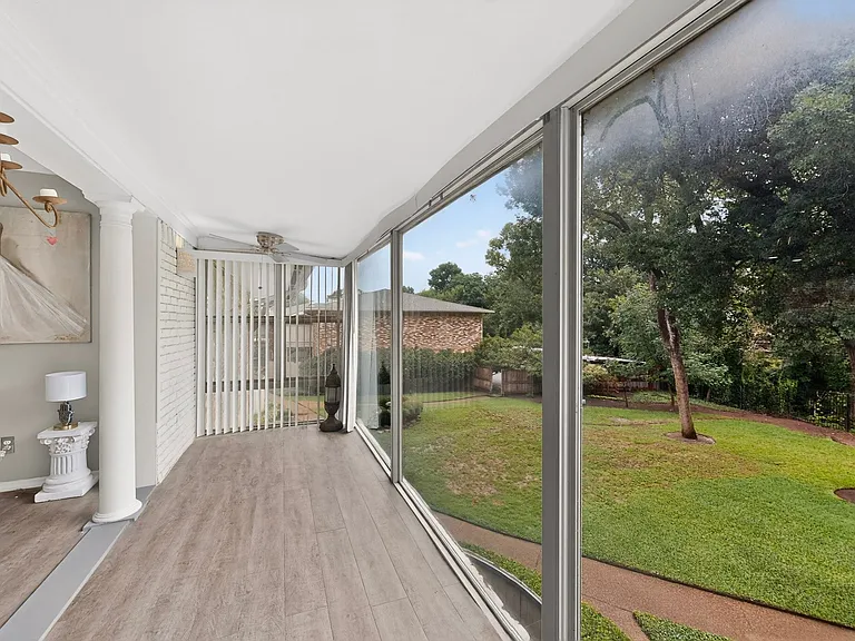 A spacious sunroom with a ceiling fan, offering a comfortable space to enjoy the scenic outdoor view.