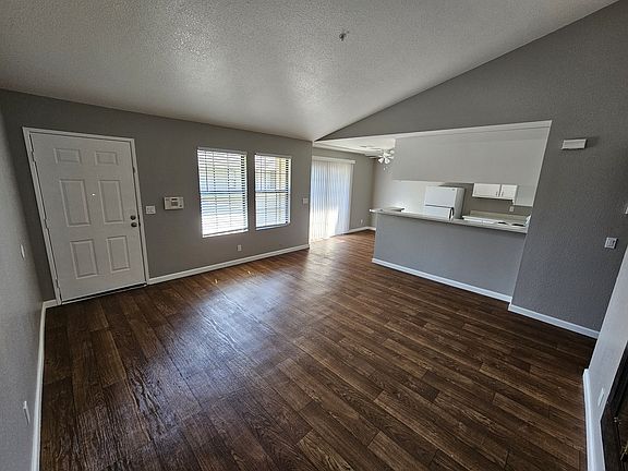Livingroom with vaulted ceiling and gas fireplace. Several windows and a front patio with extra storage.