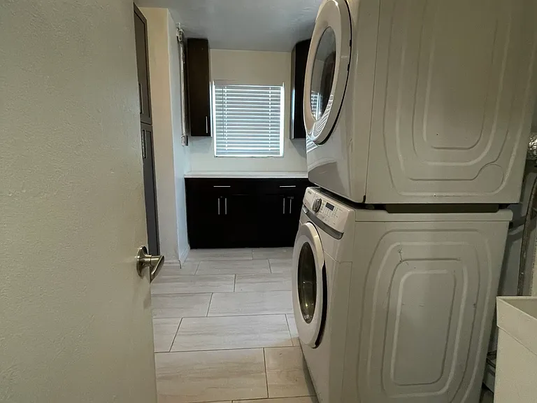 Laundry room with wrap around cabinets/storage, exterior door, utility sink, and stack washer/dryer.