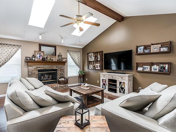 Great room with vaulted ceiling, wood beam, ceiling fan, skylights, laminate flooring and gas fireplace..
