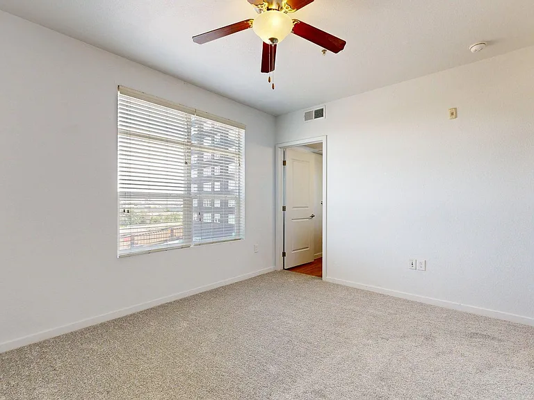 Spacious apartment bedroom with attached bathroom and plush carpet flooring.