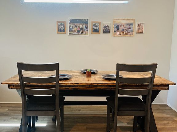 Dining area, situated between living space and kitchen, is highlighted by this wooden light fixture, adding warmth and charm to the space