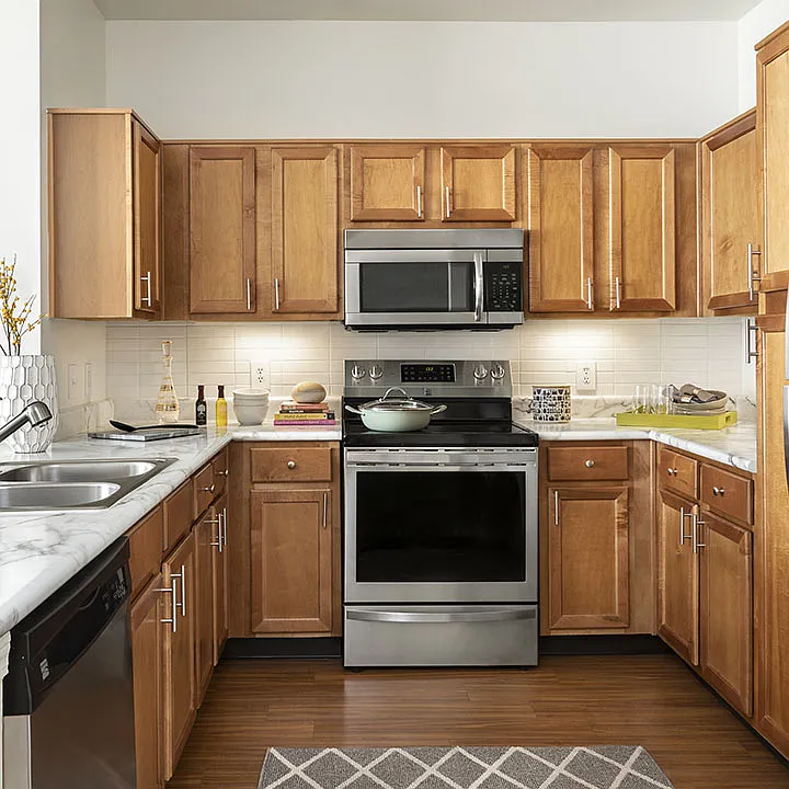 Apartment Kitchen with Stainless Steel Appliances, quartz counters and wood floors.