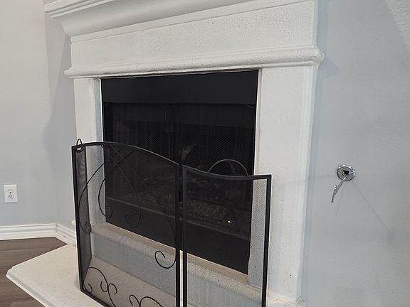 Detailed view of luxury vinyl plank floors and a gas fireplace with raised hearth