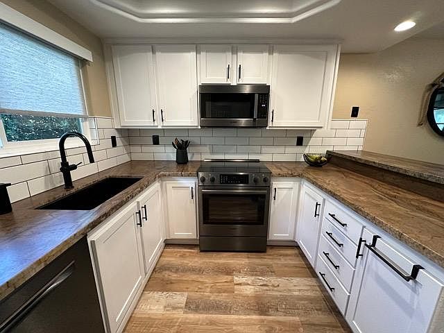 Kitchen with ample storage, oversized sink, granite counters, black stainless Bosch appliances: electric range/oven, dishwasher, microwave, refrigerator.