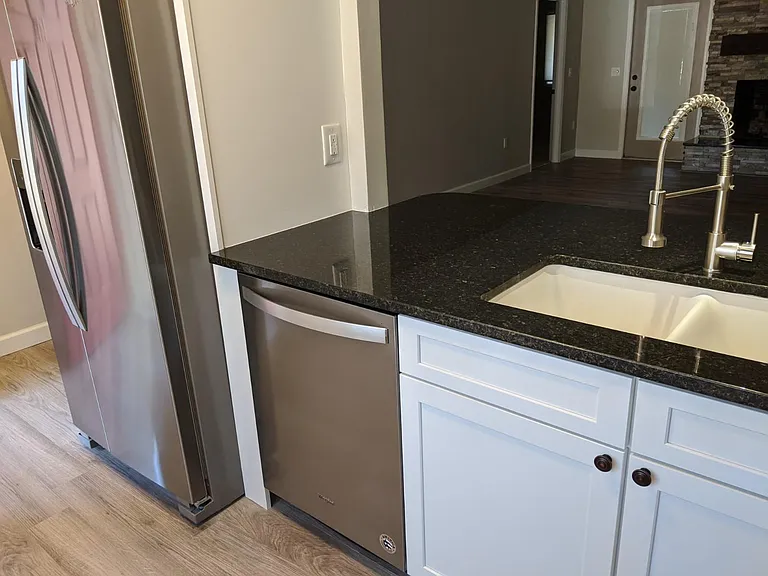 Kitchen sink, stainless dishwasher, and full size refrigerator.