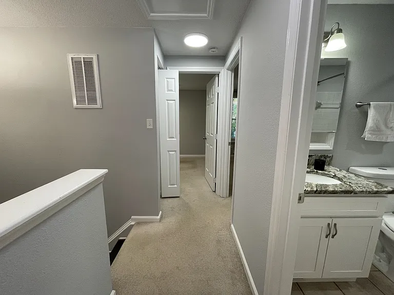 Hallway leading to additional two bedrooms. Right - hallway bath. Left - linen closet with bright lighting above.