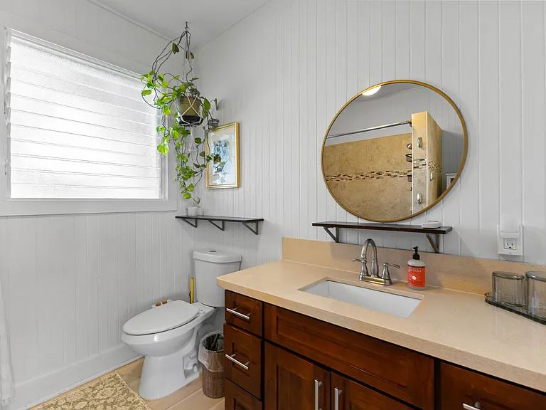 Large bathroom with high ceilings, ceiling fan, window, vanity with storage, bidet, bathtub and shower.