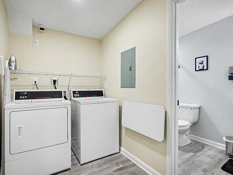 Dedicated laundry area w/full-size Speed Queen washer & dryer w/QR code, folding table & ironing board w/iron for member use
