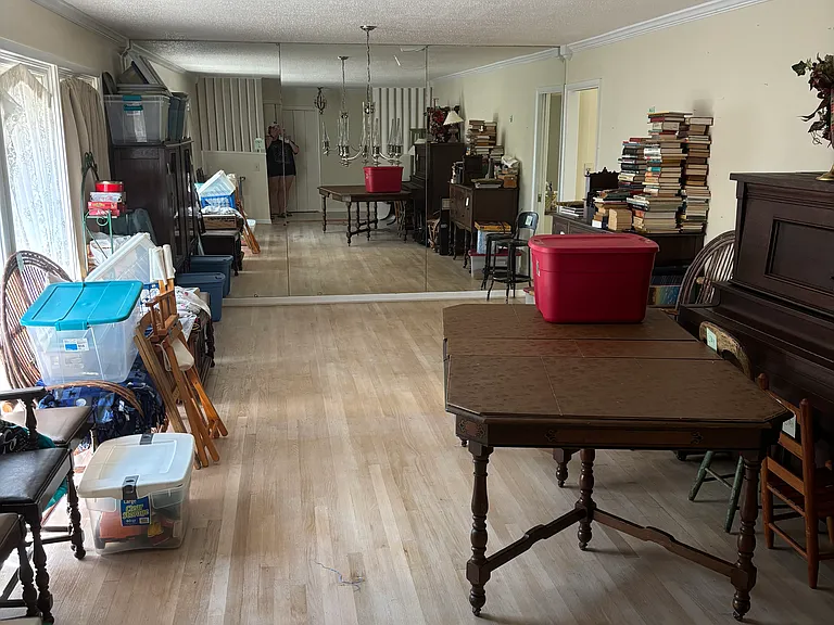 Large living room and formal dining room area with one mirrored wall and large windows looking onto walled off front porch.