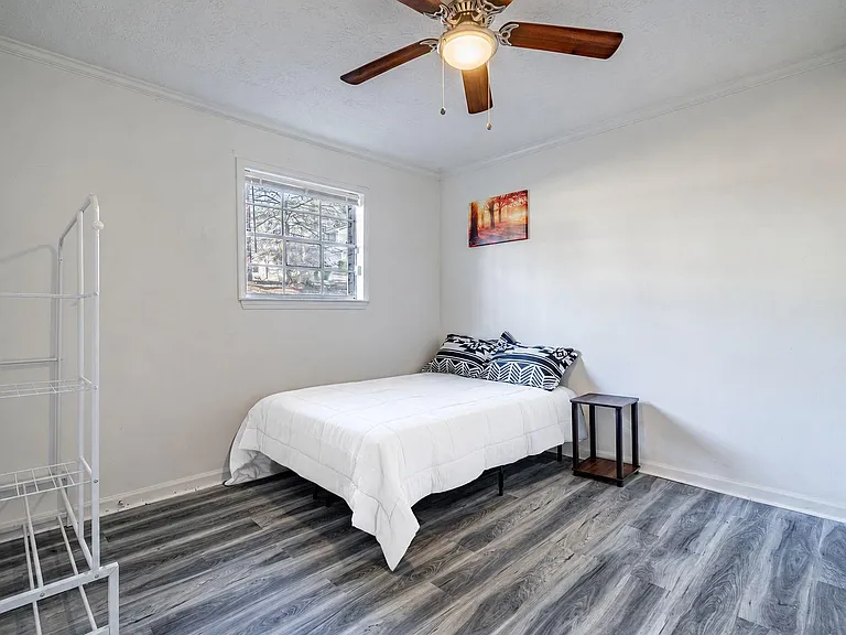 Bedroom with ceiling fan, large window, and space for a bed plus storage; durable flooring for easy upkeep.