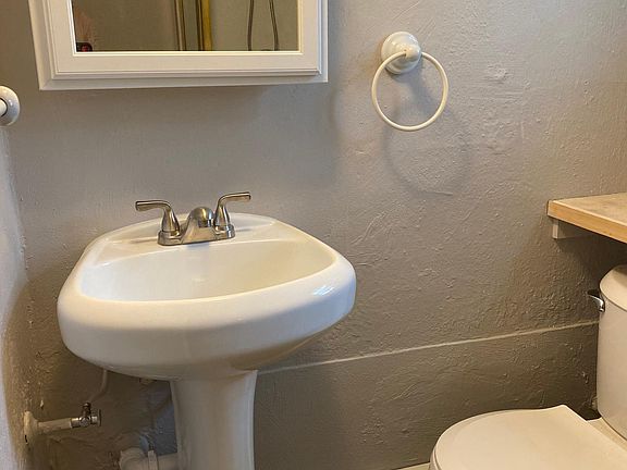 Bathroom features a river rock lined shower, pedestool sink, and glass block window for nice ambiance.