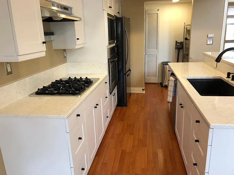 new white quarts counter top, new sleek appliances, sink, white kitchen cabinets, and washer dryer