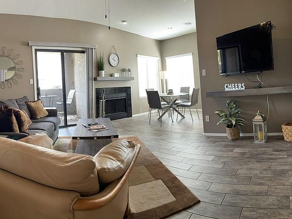Panoramic view of living, dining area and covered porch through sliding doors. Note wood grain tile through out.