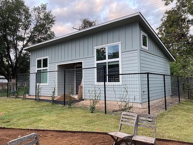 ADU exterior. Jasmine is planted to provide privacy between houses. Grass shown is owner's yard, not the ADU. Black Labrador will be in that yard occasionally.