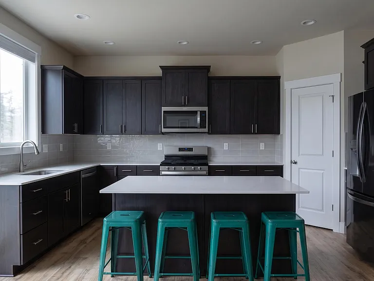 Kitchen features an island with seating, ample dark cabinetry, tile backsplash, and stainless steel appliances.