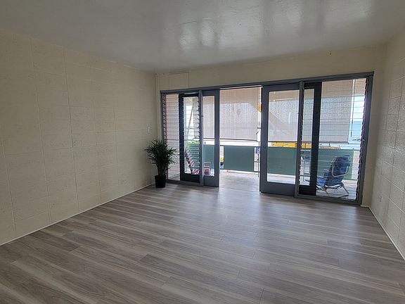 Living area looking towards Poka'i Bay. Outdoor roller shades drawn on lanai. Unit faces west.