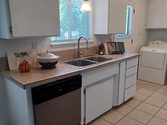 Stainless dishwasher, modern pull-down stainless faucet and pendant lighting over kitchen sink
