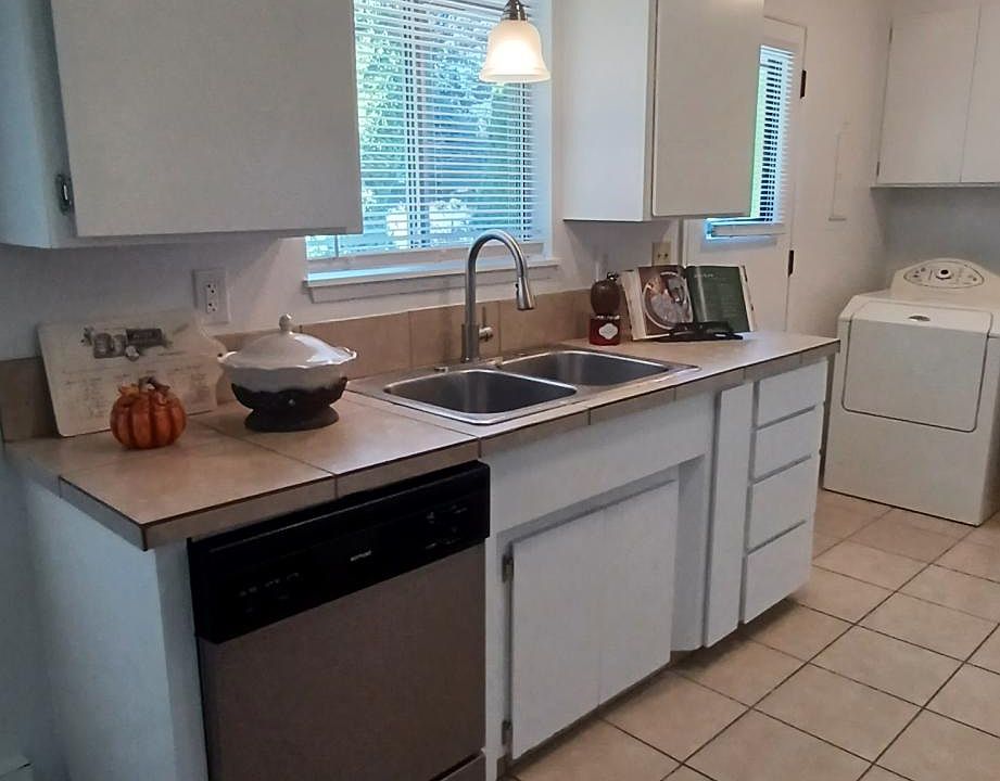 Stainless dishwasher, modern pull-down stainless faucet and pendant lighting over kitchen sink