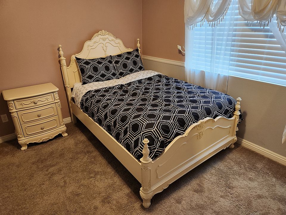 Full size bed with new bedding. Notice the window covering and the matching nightstand.