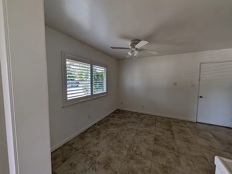 Large eating area in kitchen, tile floor and plantation shutters.