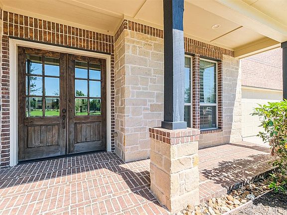 The brick walk way leads to an inviting covered patio and entry way with double doors.