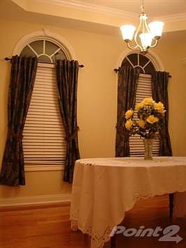 The elegant dining room features a tray ceiling, two palladium windows and hardwood flooring which has a contrasting wood frame of the dining area.