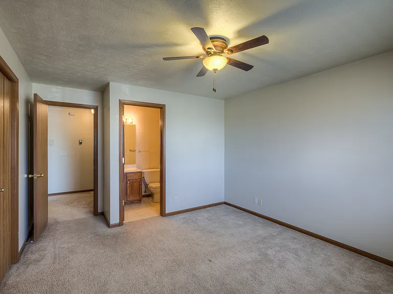 Ceiling fan in a bedroom with bathroom attached at Huntington Apartments.